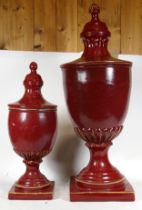 Two contemporary red painted urns and covers, each raised on square bases, together with a pair of