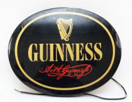 A vintage oval black and gold Guinness advertising light, by AGS signs, 60 x 48cm.