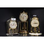 Three mid century mantel clocks with glass domes and floral details to faces.