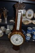 A carved oak wall mounted aneroid barometer.