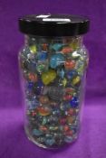 A plastic jar of mixed vintage Marbles including mixed sizes, various patterns and colours