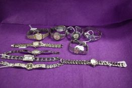Ten ladies silver tone watches, two having gold accents and one blue.