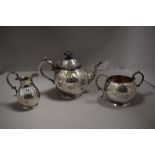 An early 20th century silver plated bachelor's tea set with embossed design and scroll worked