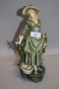 A Victorian German porcelain figure of a fish seller having a Royal Dux style glaze with slight