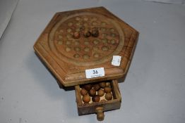 A vintage wooden solitaire board game set with counters.