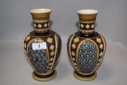 A pair of Victorian Mettlach vases having impressed ceramic design with hand decorated panels,