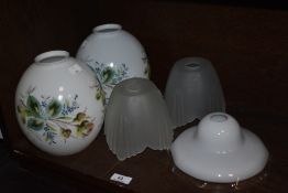 A pair of hand-painted milk glass light shades, of ovoid form and decorated with foliate sprays,