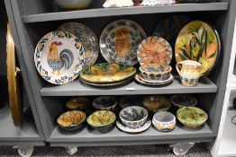 Two shelves of vintage hand crafted studio pottery most being terracotta with hand decorated designs