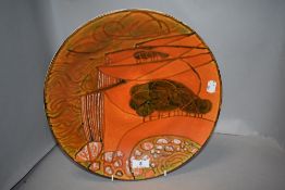 A large mid century Poole pottery Delphis charger plate decorated with a landscape scene 34cm wide.
