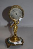 A French figural mantel clock having brass cast Pan figure holding brass cased clock on porcelain