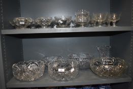 Two shelves of various cut and pressed glass items including sundae dishes, bowls and cocktail