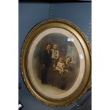 An early 20th century family photo portrait in an ornate oval gilt and gesso frame.