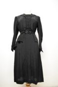 A 1930s black dress having peplum waist, gathered bodice with ladder work to front panel and collar,