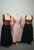 Three vintage Dirndl dresses, one in pink and two in black with iridescent copper coloured bodices