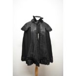 A late Victorian/ early Edwardian cape having ruffled detail to neckline and hook and eye
