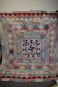 A 19th century patchwork quilt, using colourful floral fabrics and block fabrics with plain white