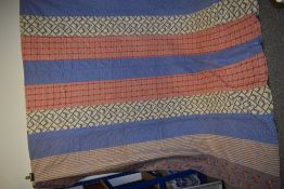 A large early 20th century quilt, using stripes of fabric with floral patterns, checks and