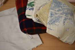 An assortment of vintage bedding and a tartan travel rug.
