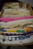 A box full of vintage and antique table linen, amongst which are embroidered examples, colourful