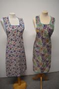 Two vibrant floral 1940s aprons, both appear unused and one still having original shop tag.