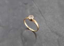 A cubic zirconia solitaire in a collared mount on a 9ct gold loop, size O & approx 1.4g
