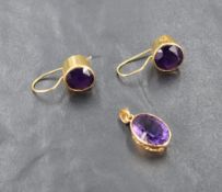 A matched yellow metal mounted amethyst pendant and earring set, the oval-cut stones within yellow
