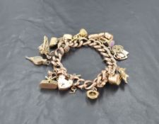 A 9ct gold and yellow metal charm bracelet, the bracelet with heart-shaped padlock clasp and moulded