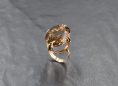 An oversized facet-cut oval smoky quartz ring in a claw-set basket mount, on a 9ct gold loop, size O