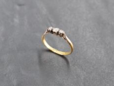 A diamond trilogy ring having three small diamonds in illusionary mounts on a yellow metal loop