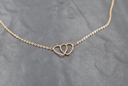 A 9ct gold necklace, having interlocking hearts between fine linked chains, marked 375, 21.grams.