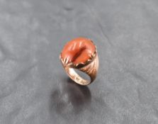An oriental rose gold ring having an oval carnelian cabouchon in a decorative collared and claw