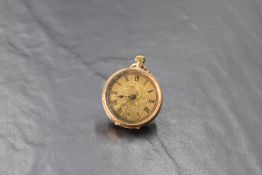 A small yellow metal top wound pocket watch stamped 14K having Roman numeral dial to engraved face