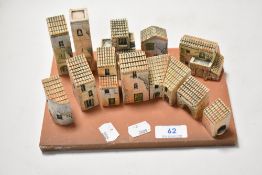 A set of mediterranean styled model ceramic houses on a terracotta base, each building being