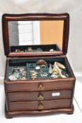 A modern wooden jewellery box housing a selection of chunky bracelets, beads, rings and more.