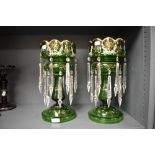A pair of Victorian green glass table lustres with clear drops, having enamel floral decoration
