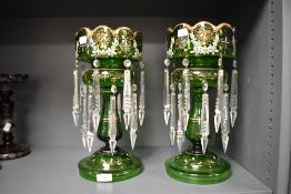 A pair of Victorian green glass table lustres with clear drops, having enamel floral decoration