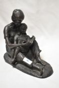 A bronze effect figurine of a mother reading with child.