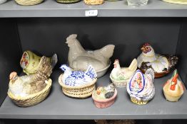 A collection of vintage and modern ceramic and glass hen storage containers and egg baskets and