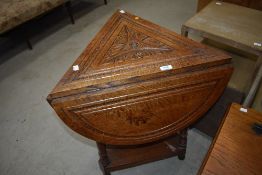 A late Victorian oak tri-form occasional table having demi lune drop flaps and carved decoration