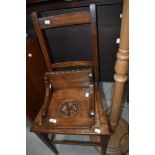 A carved oak wall sconce and a cane seated bedroom chair