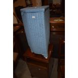 A Lloyd Loom corner linen basket and a vintage bedside cabinet