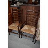 A pair of tradtional oak ladder back carver chairs having rush seats