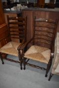 A pair of tradtional oak ladder back carver chairs having rush seats