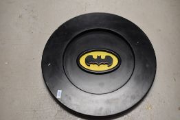 A wooden circular batman sign or plaque