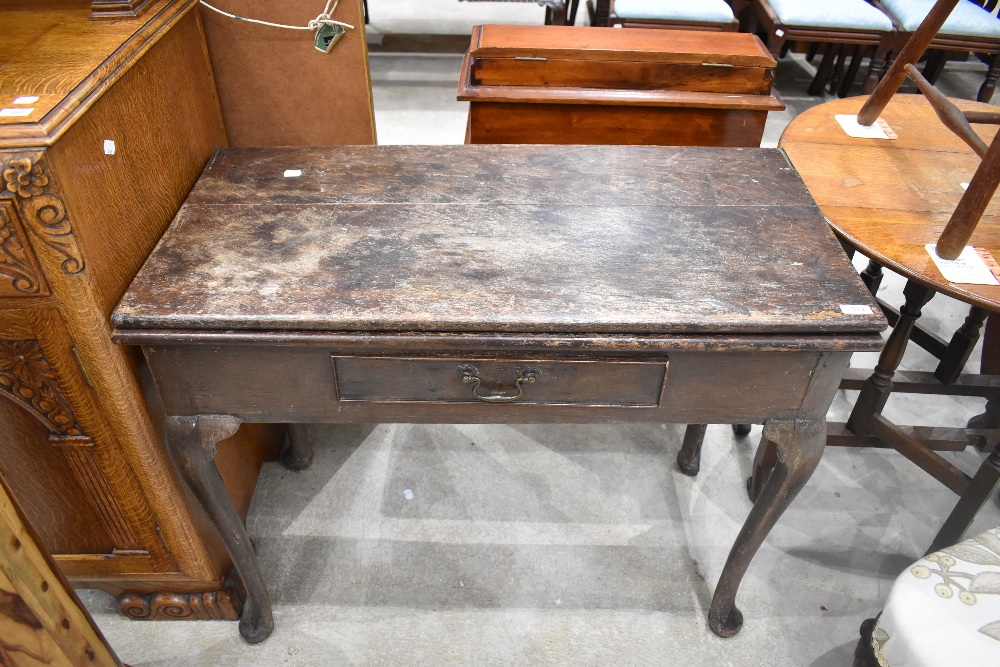 A George III oak fold over side table, the hinged rectangular top above a short frieze drawer and