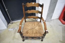 A nursing chair having oak frame with rush seat and ladder back