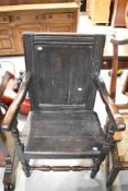 An antique vernacular Wainscott style chair in oak with panel back and seat having later