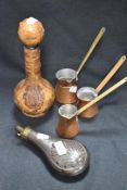 A set of three copper measures with a decanter and copper bodied shot flask.
