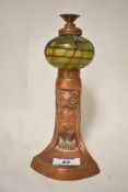 An Art Nouveau oil lamp or chamber stick cast in copper in the form of an owl with a green Loetz