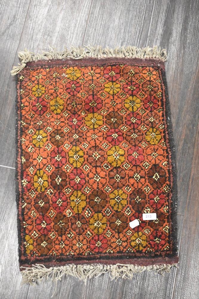 A vintage hand woven Afghan wool rug in red and brown grounds with a floral pattern with fringing